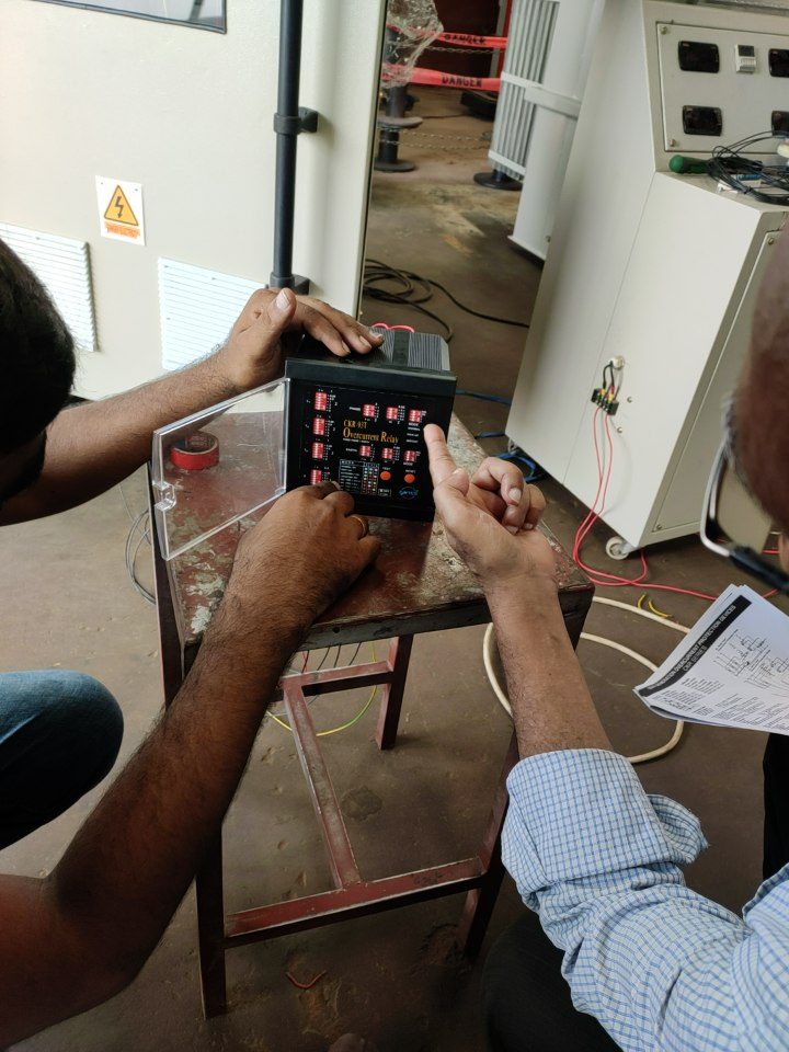 Close-up of hands setting the DIP switches on an overcurrent protection relay placed on a workbench