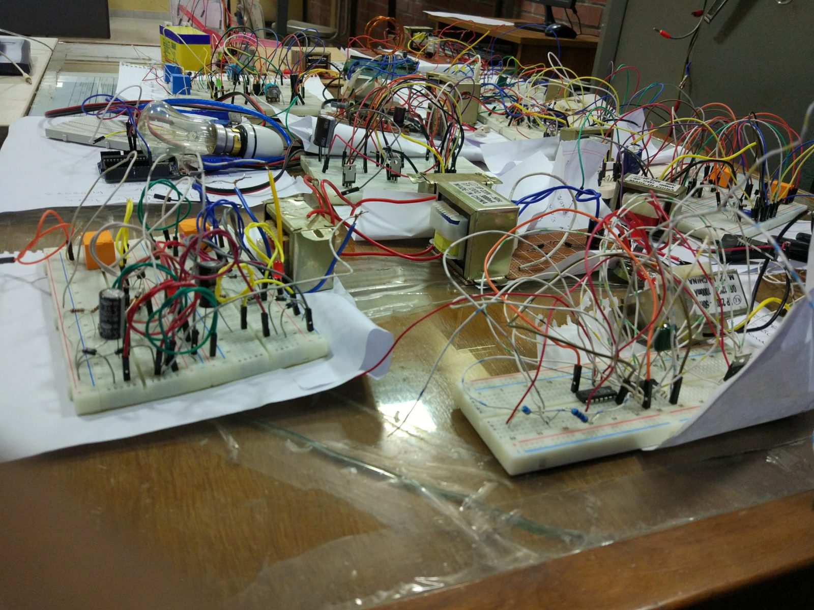 Close-up of breadboard circuits with transformers, capacitors, ICs and many jumper wires on a lab table